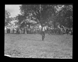 Man Walking toward the Camera with a Large Group of People Assembled in the Background